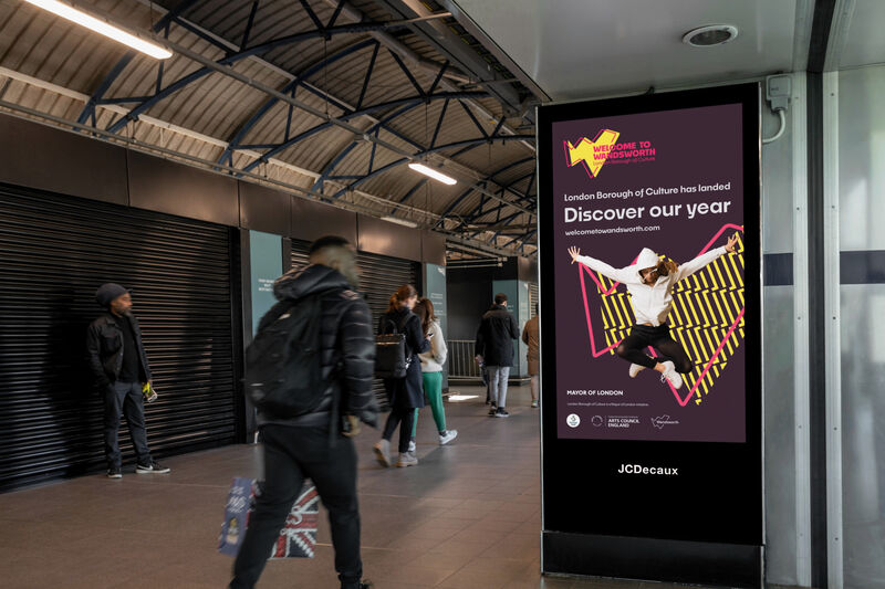 A welcome to wandsworth advert in a busy corridor in a train station