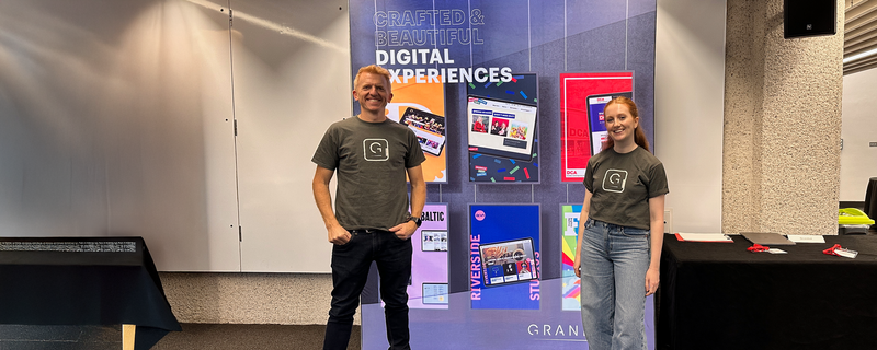 Paul and Carrigan at a conference in front of a stand