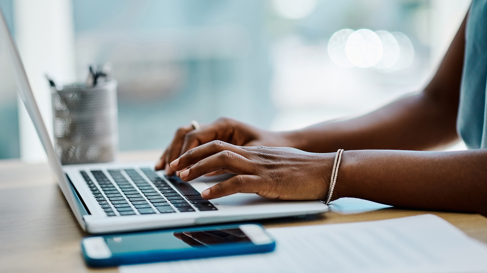 A woman's hands typing on a laptop