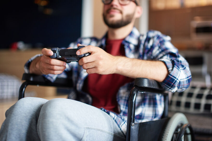 A man in a wheelchair playing a video game with a controller