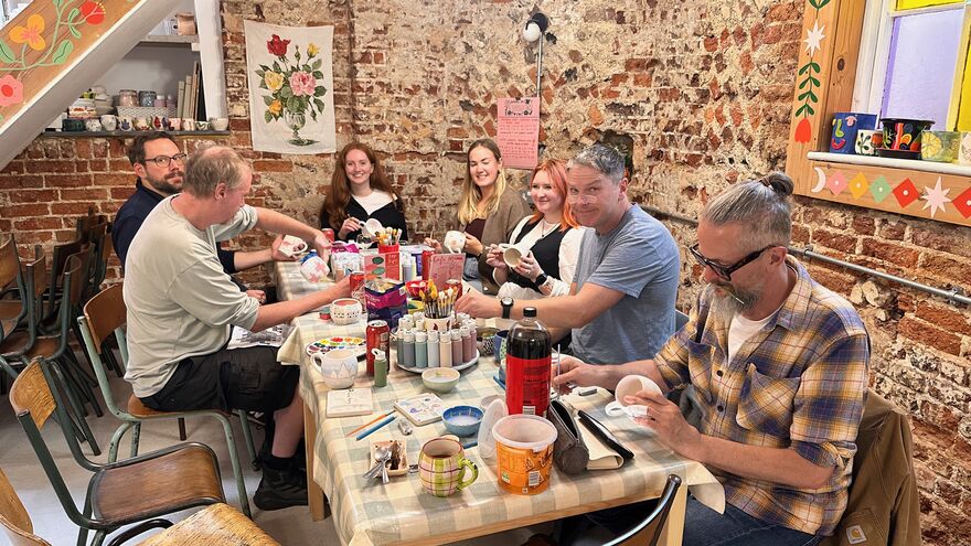 The grandad team sat around a table painting mugs