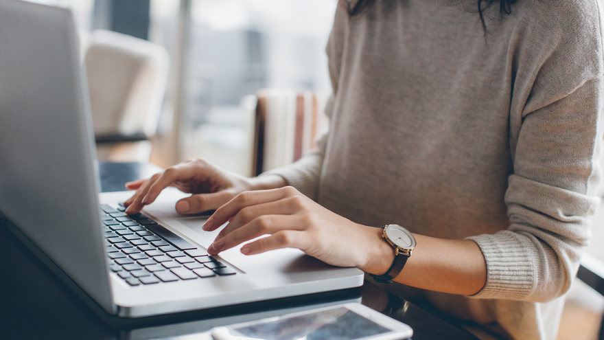 A woman types on a laptop