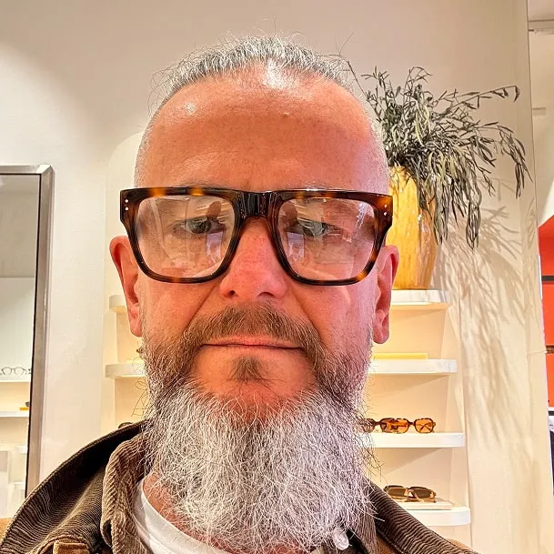 Nikolas, a white man with grey hair and a beard, wearing glasses.