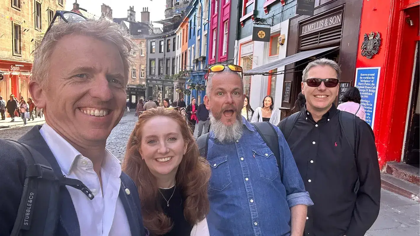 Carrigan, Nikolas and Sam sat around a table on a train, enjoying drinks and snacks.                    