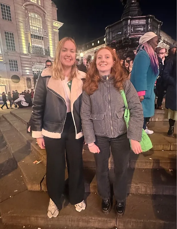 Carrigan and Emily standing happily in London at night, after seeing the Welcome to Wandsworth Piccadilly Screen.